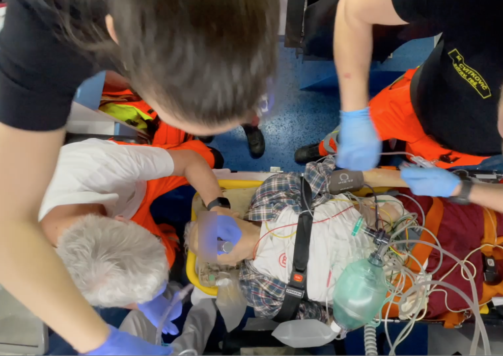 Na klic dispečerja Dispečerske službe zdravstva smo se odpeljali na nujno intervencijo k bolniku z znano aortno stenozo z bolečino v prsih in težkim dihanjem. Ob našem prihodu je nezavesten ležal na kavču. Dihanje je bilo pospešeno in otežkočeno. Krvni tlak je bil 60/40 mm Hg, pulz 130/min, zasičenost kapilarne krvi s kisikom 75%, telesna temperatura 38,9 st. C. Nad pljuči so bili slišni inspiratorni poki. V 12-kanalnem EKG posnetku nismo zaznavali ST elevacij. Po aplikaciji 100-odstotnega kisika preko maske z nepovratnim ventilom je pulzna oksimetrija narastla. Zaradi zavarovanja dihalne poti in z namernom izboljšanja ventilacije smo se odločili za endotrahealno intubacijo. Od zdravil smo uporabili fentanil, midazolam, ketamin, sukcinilholin in esmeron. Preko perifernega venskega kanala smo mu dovajali 0.9% NaCl. Ob predaji z napotno diagnozo pljučnice in septičnega šoka je imel bolnik višji tlak in normalno zasičenost krvi s kisikom.